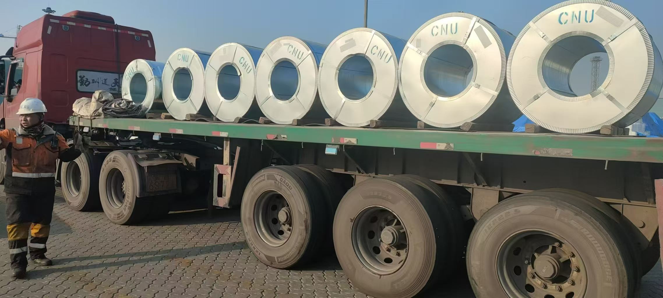 CNU shipping marks visible on wrapped coils arranged on a flatbed truck