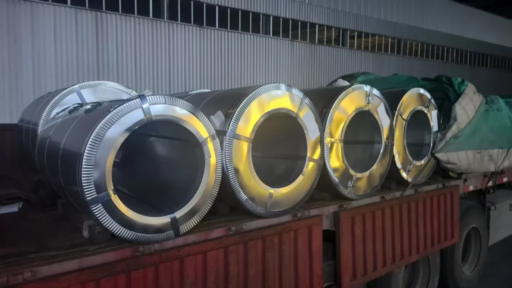 Wrapped steel coils with metal edge rings and strapping on a loading truck